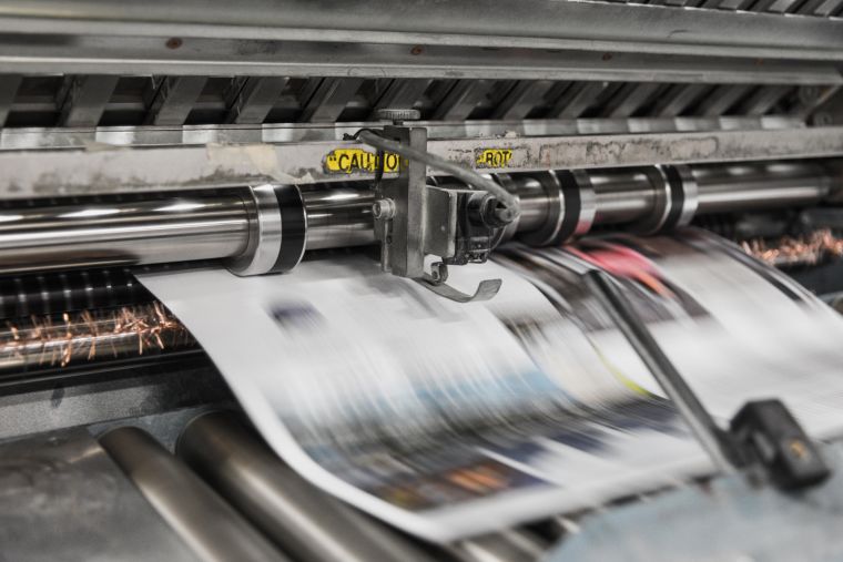 Newspaper rushing through a printing press