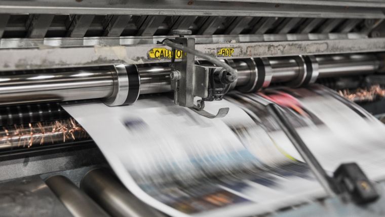 Newspaper rushing through a printing press